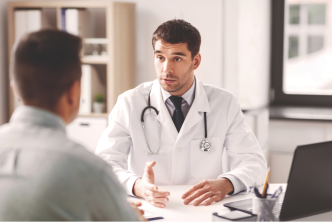 male physician talking to patient behind desk