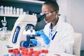 Black woman looking at a sample in a microscope in a scientific studies laboratory
