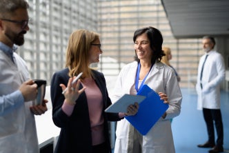 Doctors talking to pharmaceutical sales representative, presenting new pharmaceutical product.